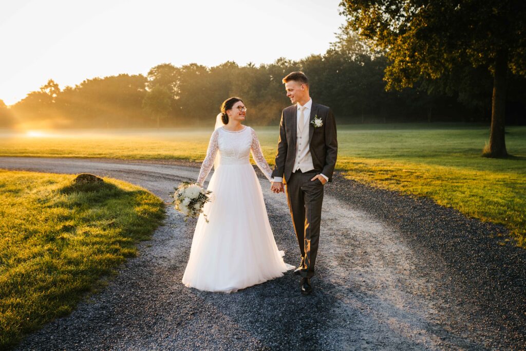 Hochzeitsfotograf-Guetersloh-Brautpaar-geht-Haendchenhaltend-im-Sonnenaufgang